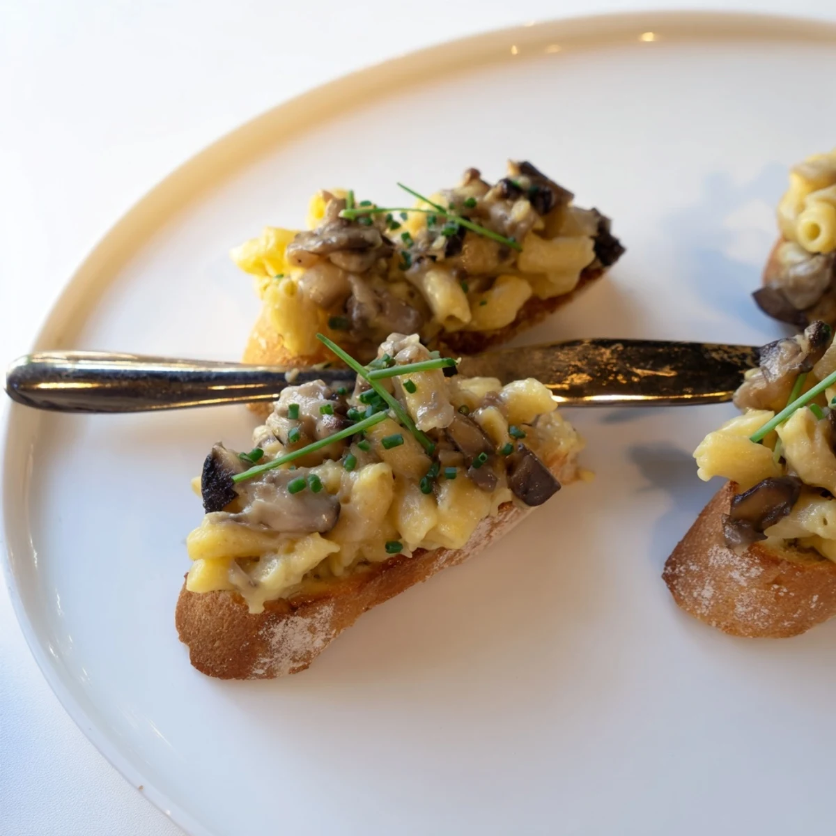 Creamy Truffled Mushroom Mac Crostini garnished with chives for an elegant appetizer.  