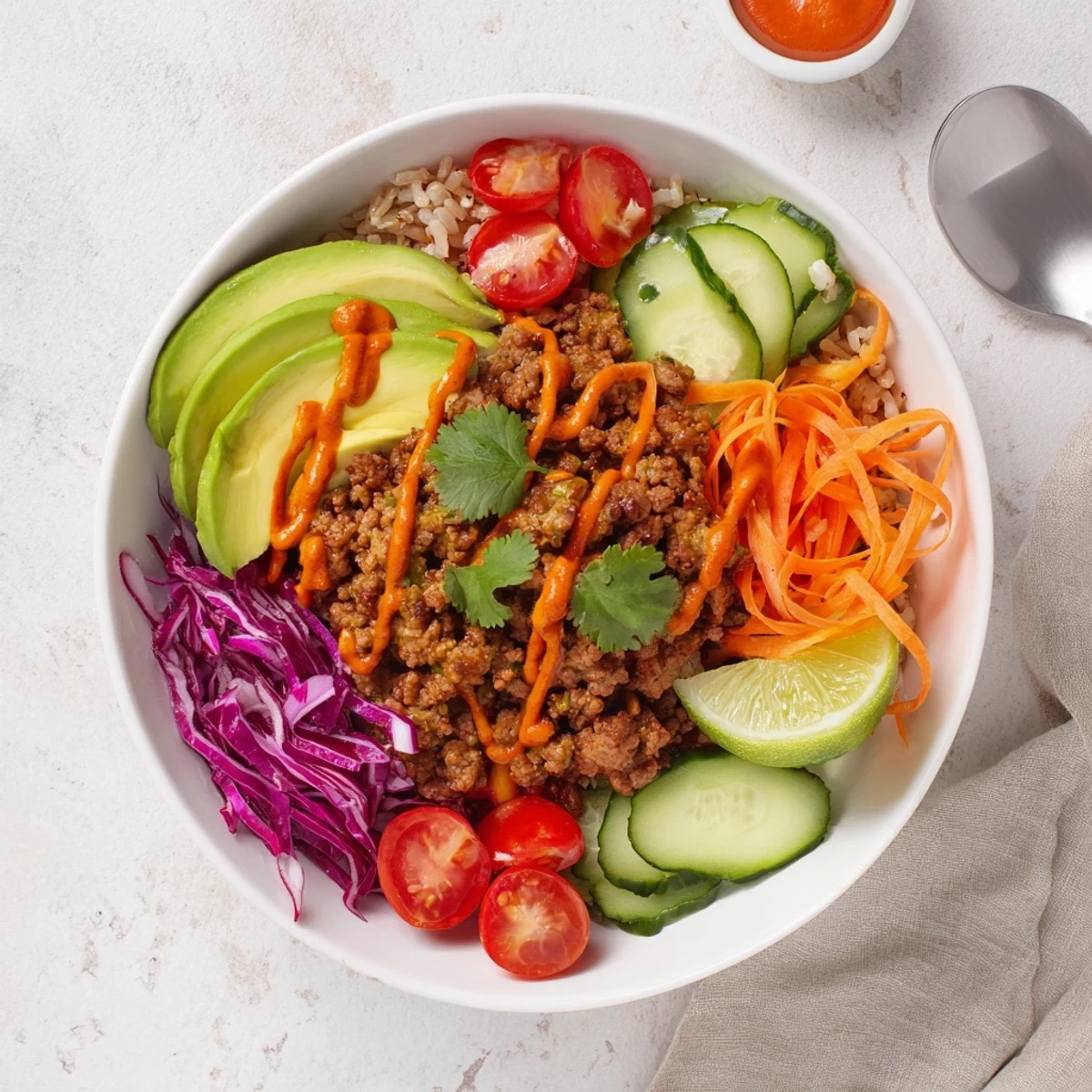 Colorful plant-based meat bowl topped with fresh veggies, avocado, and lime wedges.  