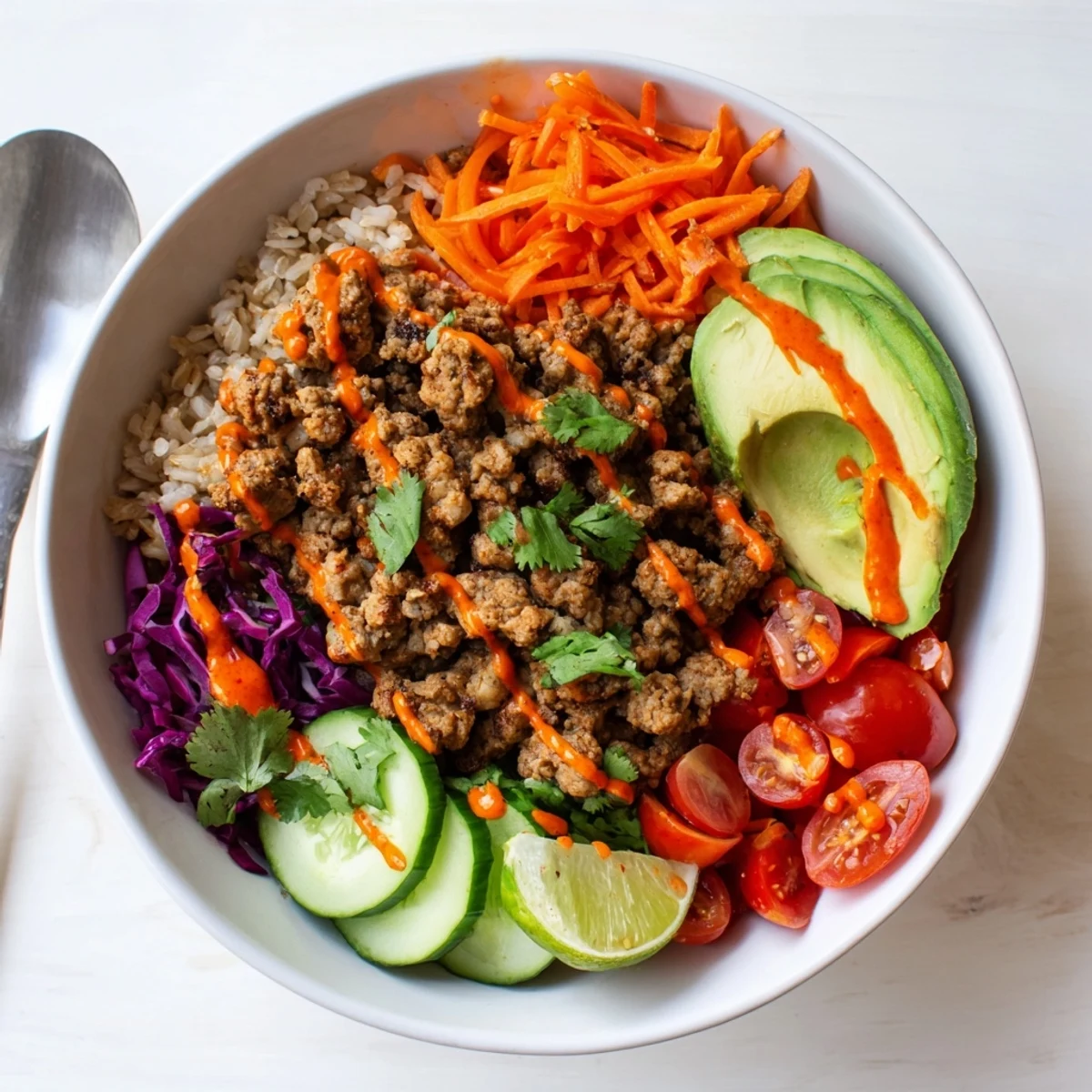 Delicious plant-based meat bowl drizzled with spicy mayo and surrounded by vibrant toppings.  