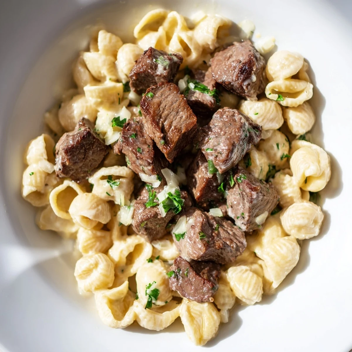 Sizzling garlic butter steak bites served atop creamy, cheesy shells, ready for a delicious dinner.