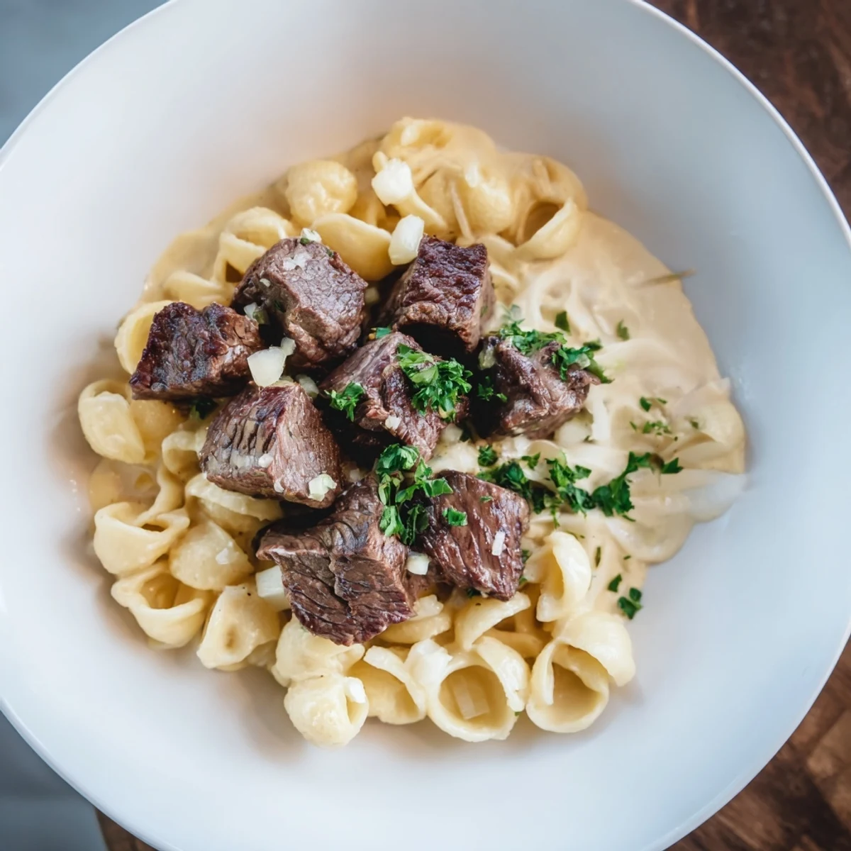 A close-up of tender garlic butter steak bites and cheesy shells, perfect for a cozy weeknight meal.