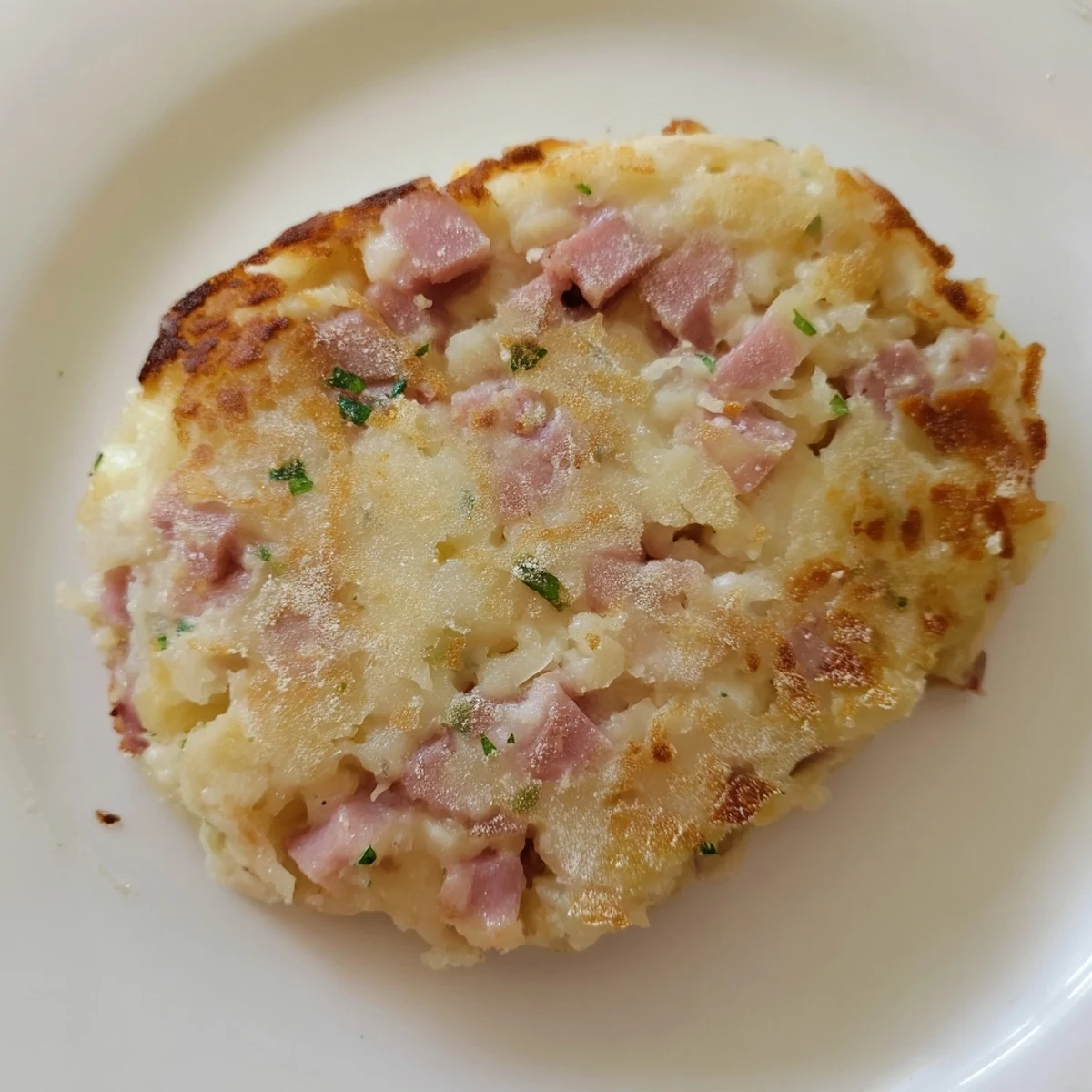 A stack of savory Depression-Era Ham & Potato Patties, with visible bits of ham and onion.