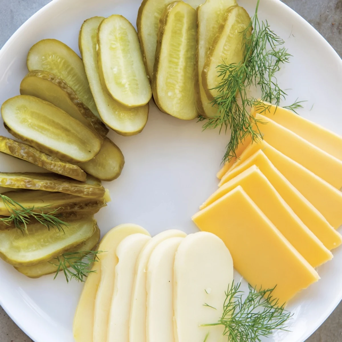 Dill pickles and cheese appetizer arranged, colorful cheese slices perfectly alongside juicy dill pickles.