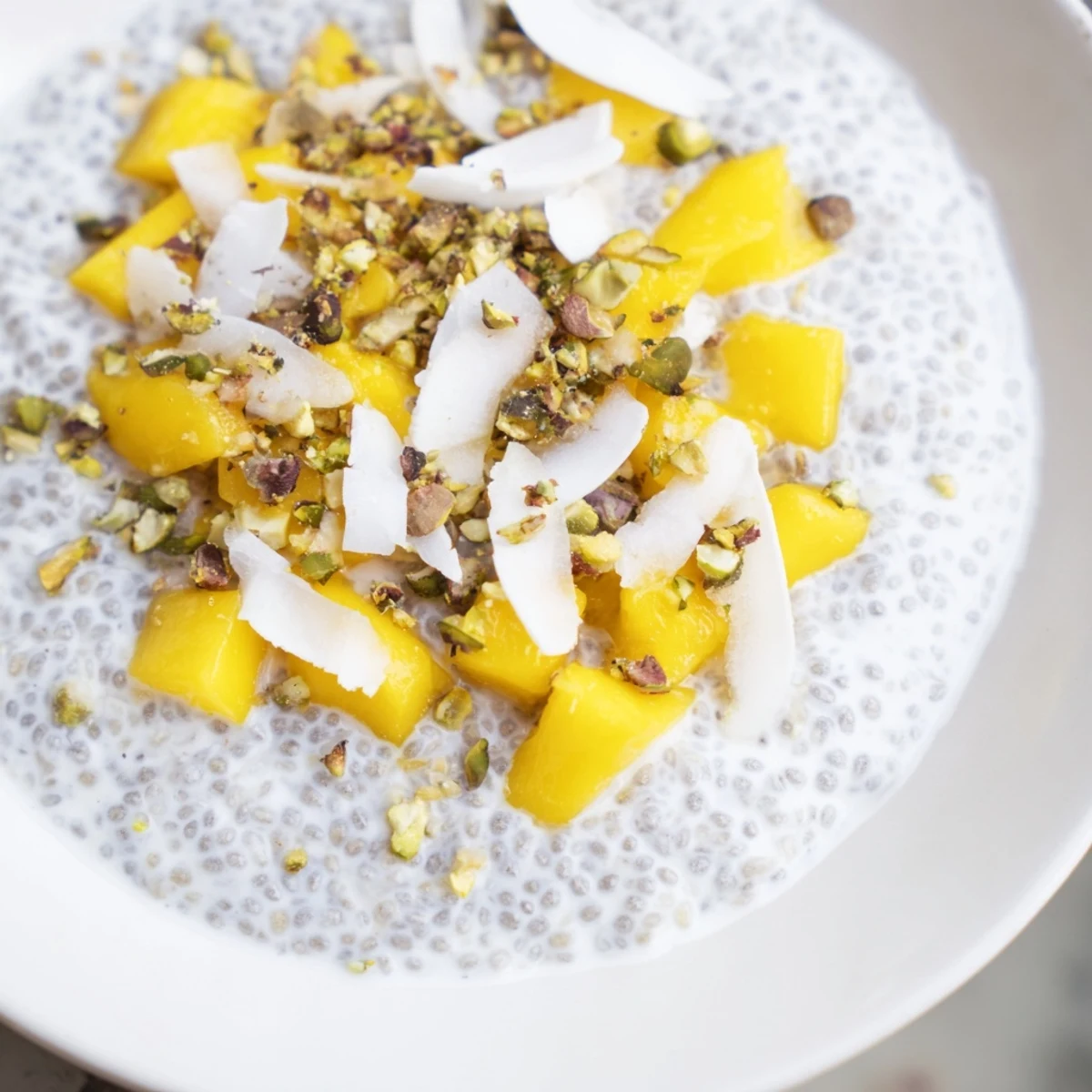 Creamy Mango Coconut Chia Pudding layered with fresh mango, ready to eat with a spoon.