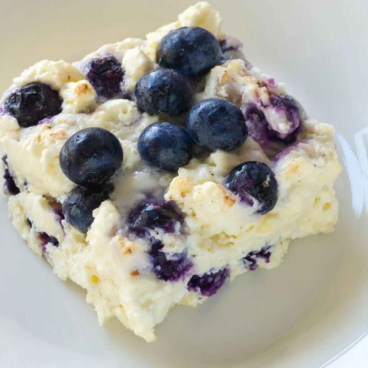 A close-up of a warm slice of Blueberry Cottage Cheese Bake, ready to enjoy for breakfast.