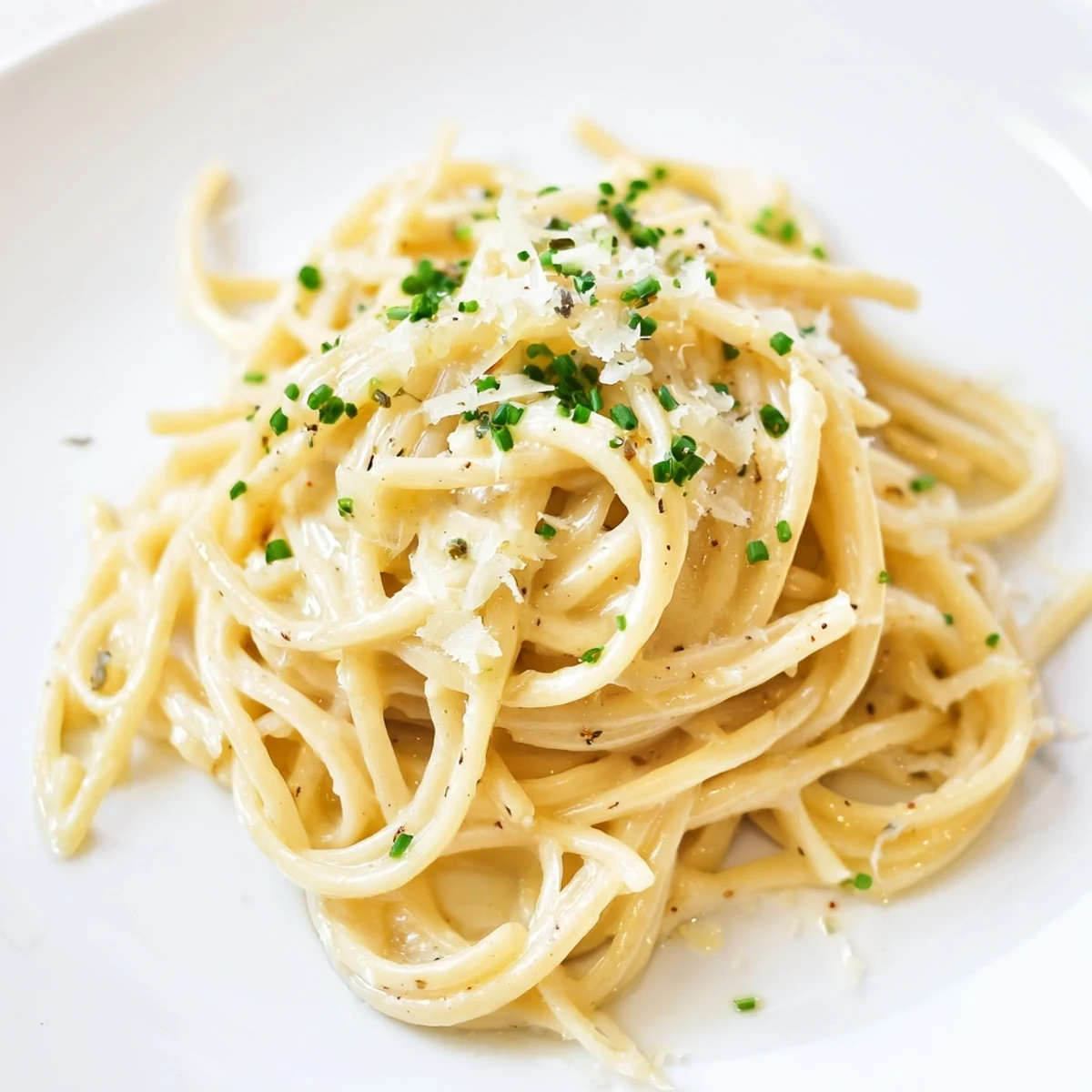 Steaming plate of miso butter pasta, glistening noodles tossed with creamy parmesan and fresh herbs.