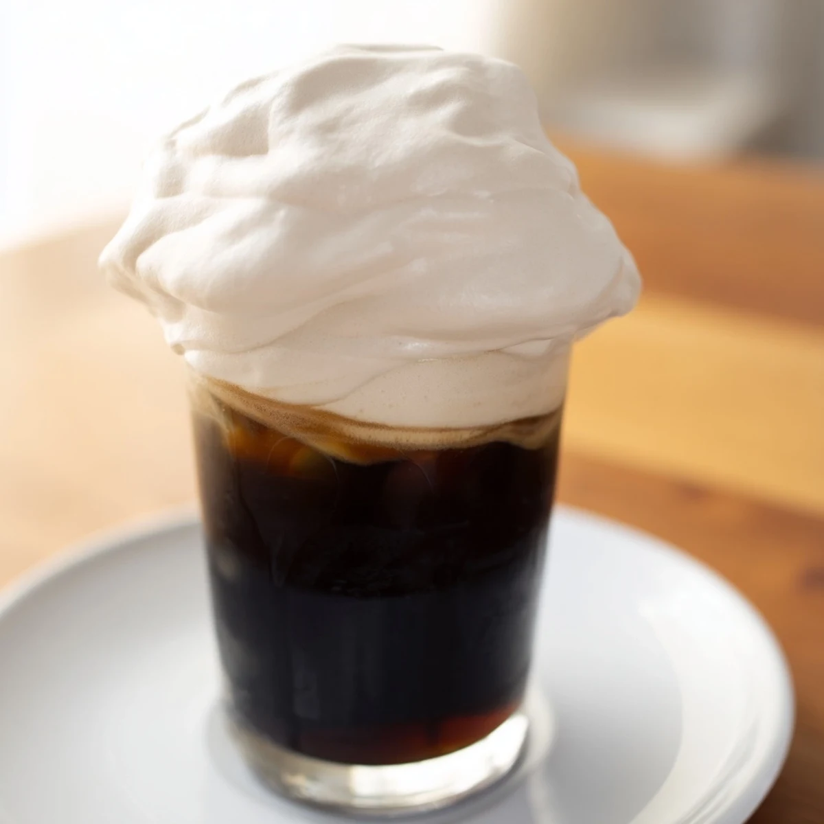 Fluffy Starbucks Cold Foam sits atop a cold brew, creamy vanilla scent filling the air, perfect topping.