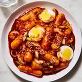 A close-up of spicy, saucy Korean Tteokbokki, a vegetarian-friendly street food delight, ready to eat.