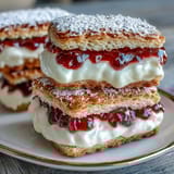 Delicious clotted cream shortbread sandwich cookies filled with tangy raspberry jam for a classic British teatime treat.