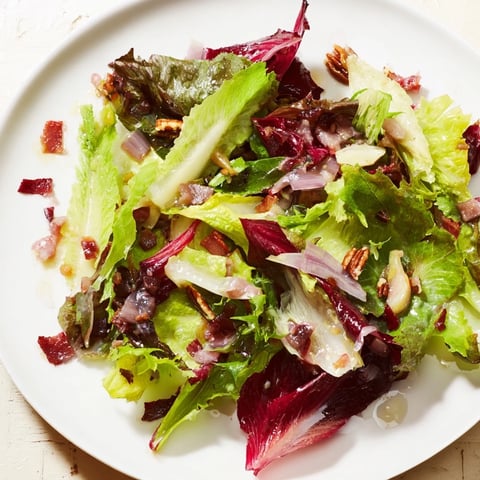 Close-up of a Bitter Greens Salad with Warm Bacon Dressing, highlighted by crispy bacon and soft greens.