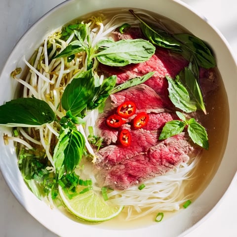 Steaming bowl of Vietnamese Pho Express with herbs and thinly sliced beef, ready to enjoy.