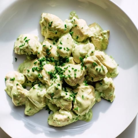 Sliced tomatoes and red onions top the Avocado Ranch Chicken Salad, drizzled with bright green dressing and ready to serve.