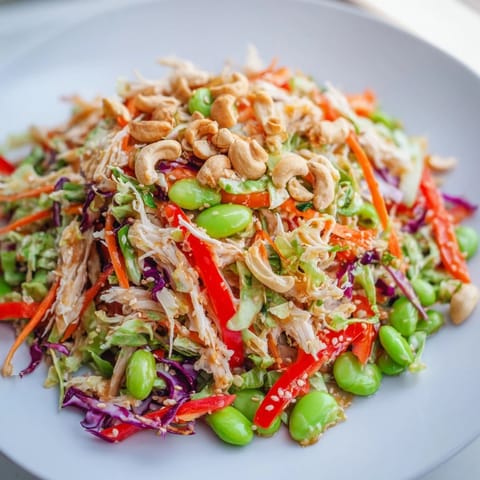 Serving suggestion for Edamame Crunch Chicken Salad, topped with toasted sesame seeds and cashews on a bright plate for a light lunch.