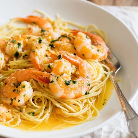 A close-up of vibrant Lemon Butter Shrimp Pasta Lite with tender pink shrimp and a glistening, aromatic lemony butter sauce.  