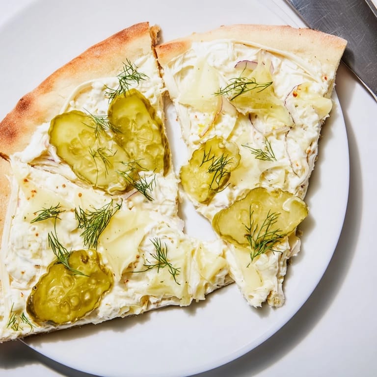 Sliced Pickle Pizza emerging from the oven, showcasing rich crème fraîche and savory toppings.