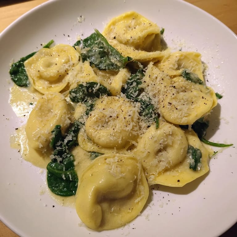 Enjoy a forkful of Creamy Spinach Alfredo Tortellini, a vibrant vegetarian pasta dish with delicious flavors.