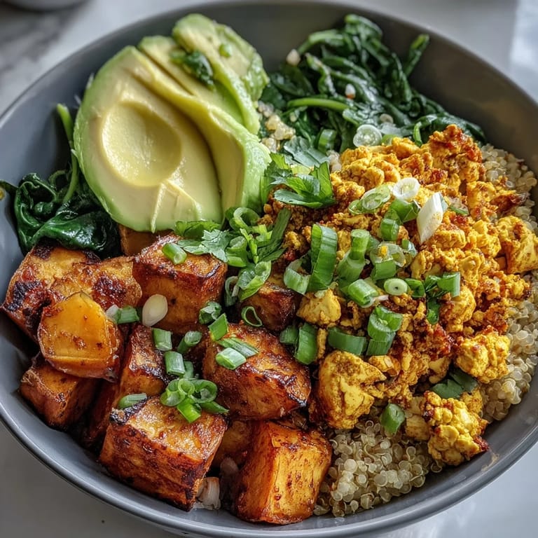 Freshly prepared Tofu Scramble Vegan Breakfast Bowl topped with sautéed spinach, fluffy quinoa, and sliced green onions.