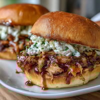 Juicy pulled pork sliders with tangy barbecue sauce and crunchy coleslaw on soft slider buns, perfect for a baby shower celebration.  